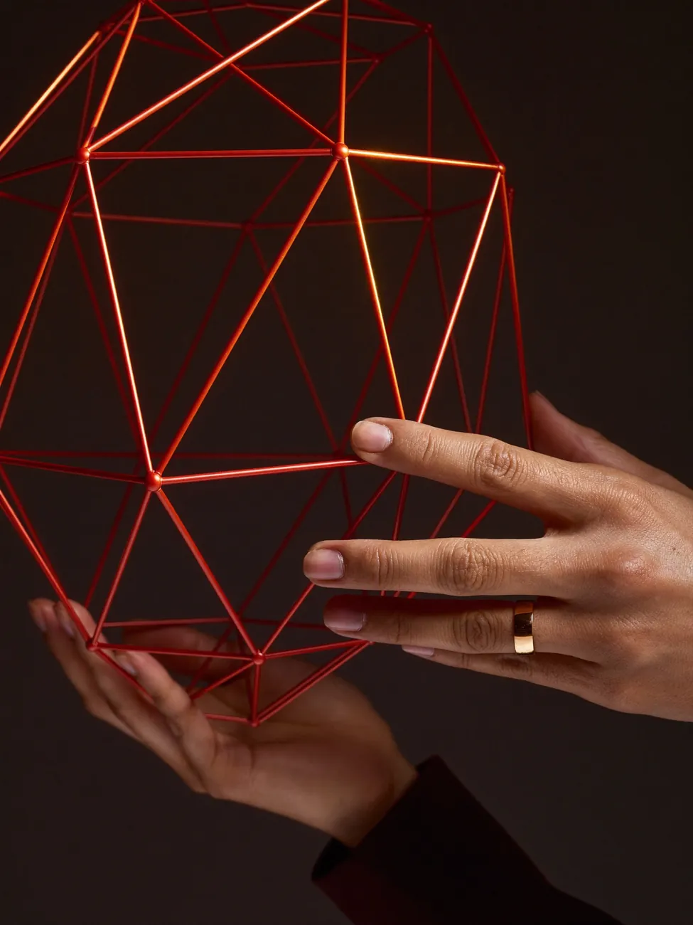 Hands holding a glowing red geometric wireframe