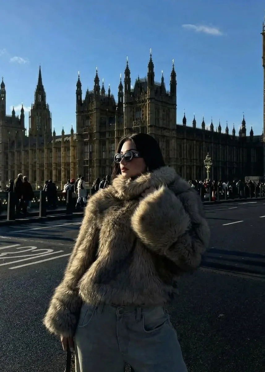 A model in a shearling coat before a gothic palace